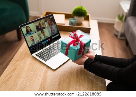 Thank you for my present! Person seen from behind at home showing a gift and celebrating her birthday with friends on a video call 