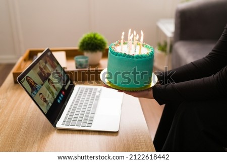 Celebrating my birthday alone. Young person with a cake while her friends sing happy birthday on a online video call 