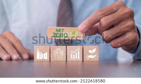 Hand puts wooden cubes with net zero icon in Net zero on grey background. Net zero by 2050. Carbon neutral. Net zero greenhouse gas emissions target. Climate neutral long term strategy. Royalty-Free Stock Photo #2122618580