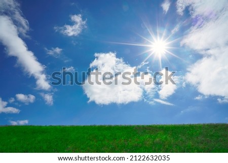 Grass hills on horizon in steppe under white clouds sky during sunset with sun light beams. nature background. summer or spring season. empty copy space for inscription. Grassland. straight horizon