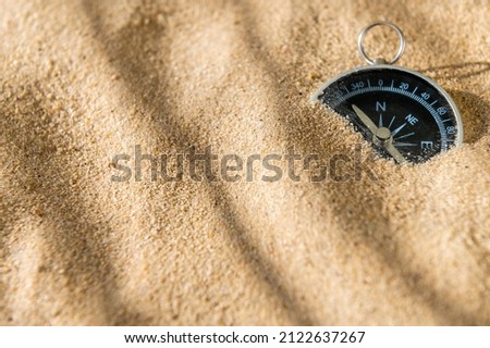 Compass on the sand at the beach. Concept of travel or direction