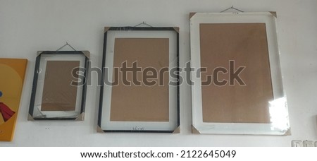 three frames of different sizes and different colors on a white wall
