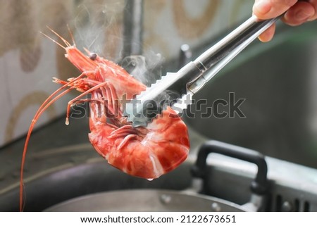 Chef cooking with Red cooked prawn or tiger shrimp.