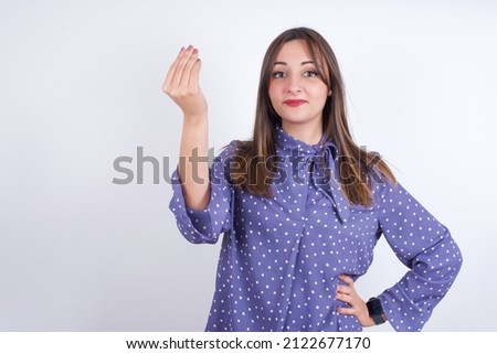 What the hell are you talking about. Shot of frustrated Young arab woman wearing polka-dot clothes over white backgtound gesturing with raised hand doing Italian gesture, frowning, being displeased  Royalty-Free Stock Photo #2122677170