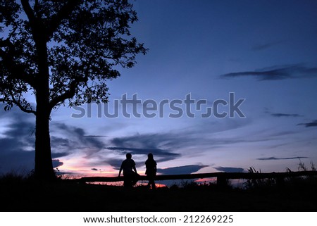 Young couple enjoying the sunset under the tree