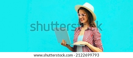 Portrait of modern young woman working with laptop on blue background