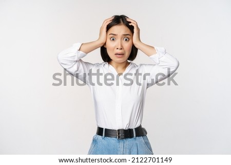 Image of shocked anxious asian woman in panic, holding hands on head and worrying, standing frustrated and scared against white background Royalty-Free Stock Photo #2122701149