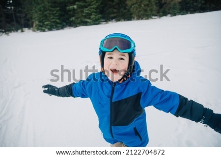 portrait of a child in a helmet and ski goggles. Little boy on the slope. Child with ski equipment smiles and has fun on the slope. Child in ski school learns to ski