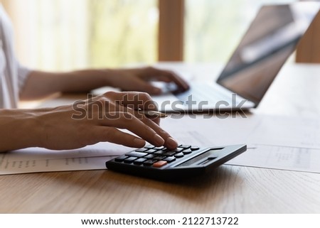 Close up cropped young woman calculating household expenditures, managing monthly budget, involved in financial accounting using computer applications, paying for services online, investment concept. Royalty-Free Stock Photo #2122713722