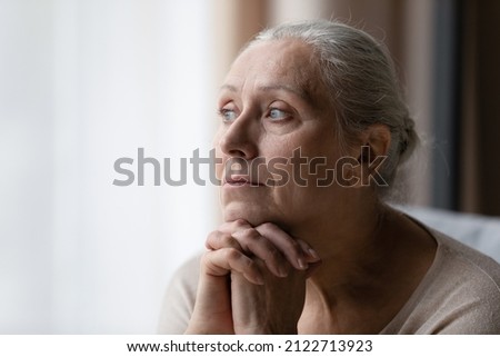Thoughtful bored older 70s woman looking at window, feeling depressed, frustrated, lonely, suffering form memory loss, dementia, Alzheimer disease, mental disorder. Old age problems concept Royalty-Free Stock Photo #2122713923