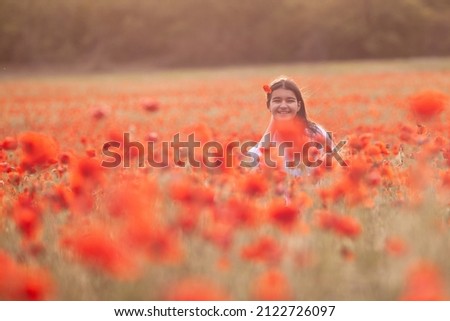 Beautiful girl in a white dress on a poppy field