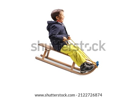 Boy smiling and sliding on a wooden sleigh isolated on white background
