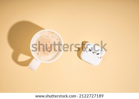 Coffee, wireless headphones on a beige background. Flat lay, top view 