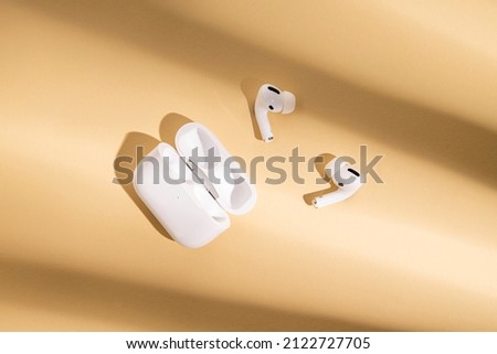 Wireless headphones on a beige background. Flat lay, top view