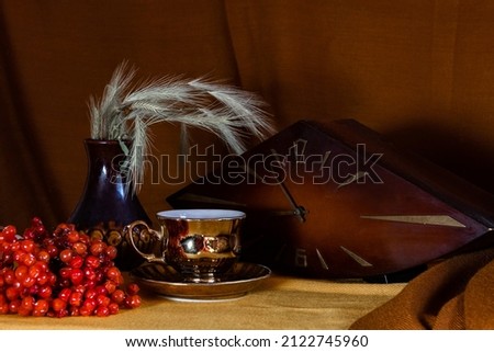 Still life: viburnum, cup, clock on the table