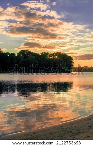 soft focus of picturesque scenic view photography with sunset lighting around island background and foreground sand beach and river water, vertical format, cloudy weather, silent moody atmosphere