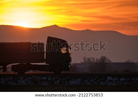 Semi-truck with cargo trailer driving on highway hauling goods in evening. Delivery transportation and logistics concept Royalty-Free Stock Photo #2122753853
