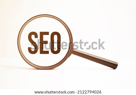 Magnifying glass with text SEO on wooden table.