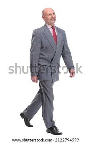 full length picture of a senior business man walking towards the camera and smiling.