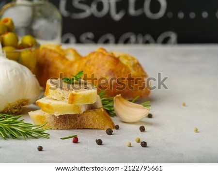 Appetizing goose liver foie gras on slices of fresh baguette. garnished with parsley sprigs on top. Garlic, greens. black pepper on a white background. Restaurant, hotel, banner.