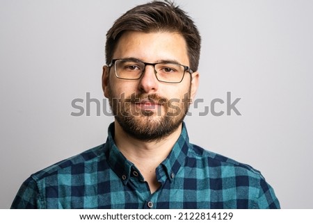 Portrait of one adult caucasian man 30 years old with beard and eyeglasses looking to the camera in front of white wall background serious wearing casual shirt copy space Royalty-Free Stock Photo #2122814129