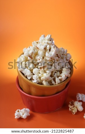 Close Up Photo of Popcorn on a Stuffed Orange Bowls and Pop Color Background. Isolated. 