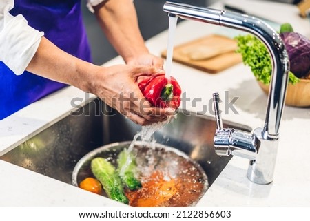 Portrait of man chef cooking and preparing wash fresh vegetables salad splashing in water with cook food on counter standing in the restaurant commercial kitchen Royalty-Free Stock Photo #2122856603