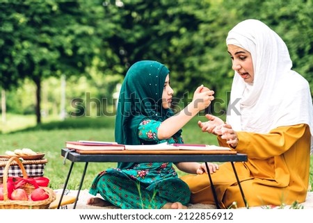 Portrait of happy religious enjoy happy love asian islam family muslim mother and little muslim girls child with hijab dress smiling and having fun moments good time in summer park
