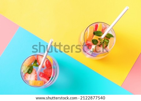 Two glasses with fruit iced tea drinks on a colorful backgrounds top view.