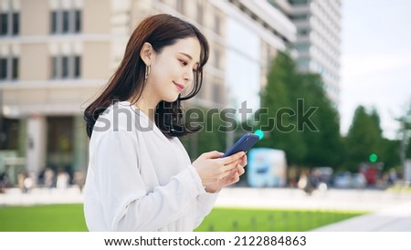 Young Asian woman using a smart phone in the city.