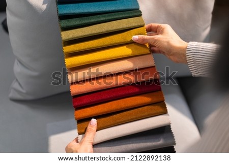 The woman chooses the fabric on the sofa. A young women looks at tissue samples. Selects the color of the sofa. Textile industry background. Tissue catalog