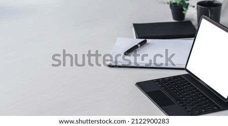 Creative workspace with white screen digital tablet and magic keyboard on white table.