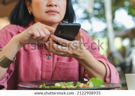 woman use mobile phone take a photo of salad before eating in restaurant