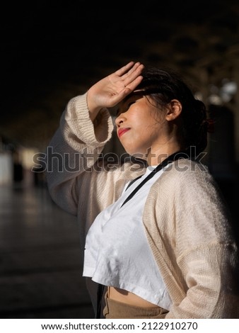 Portrait photography Asian woman beautiful long hair wearing white shirt model blocking sunlight on sunny hot day.Standing at train station(Bangkok), travel vacation during the evening of the day.