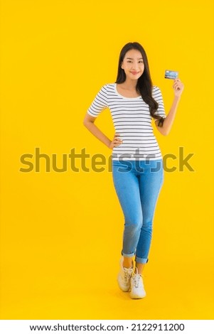 Portrait beautiful young asian woman show credit card for online shopping on yellow isolated background