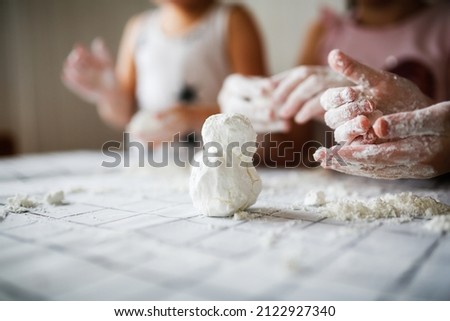 Funny children play with artificial snow at home in the kitchen. Educational classes and experiments with children at home. Sensory development and games at home. Snow from starch and shaving foam