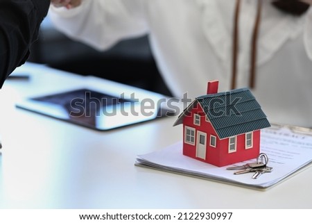 House model, keys and contract document on white table.