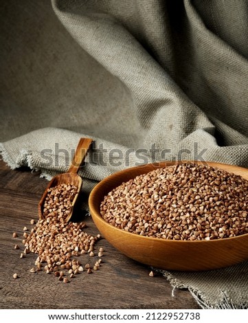 Organic buckwheat groats in a wooden bowl with a spoon on a linen napkin on a wooden table. Banner. Rustic style. Healthy nutrition concept. Buckwheat contains a large amount of vitamins and minerals. Royalty-Free Stock Photo #2122952738