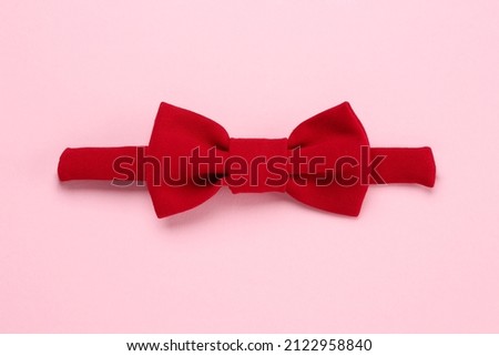 Stylish red bow tie on pink background, top view