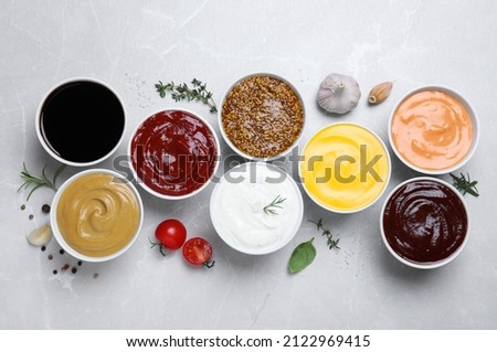 Many different sauces on light grey table, flat lay