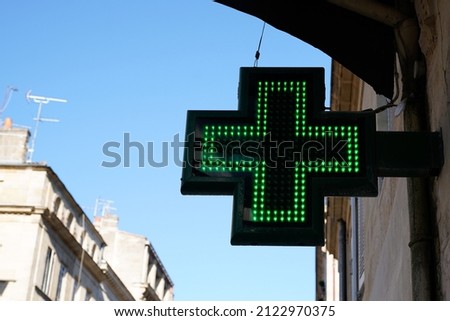 green cross black lighting logo sign on wall building of pharmacy entrance