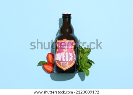 Bottle of tasty strawberry kombucha and mint on blue background