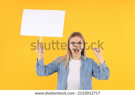 Young woman with blank protest sign on yellow background