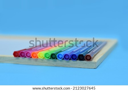 Selective Focus of A Set of Colourful Magic Ink Pens On A Wooden White Board Isolated with Blue Background 