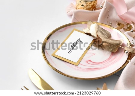Beautiful table setting and wedding invitation on light background