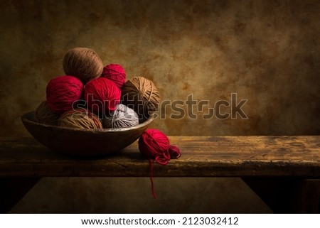 Still life of an old bowl of red wool balls on a rustic old wooden shelf. This is suitable for digital compositing.