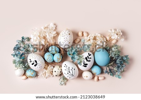 Easter eggs with sweets and flowers on beige. Happy Easter concept. White and blue eggs and cute nest with candy  Royalty-Free Stock Photo #2123038649