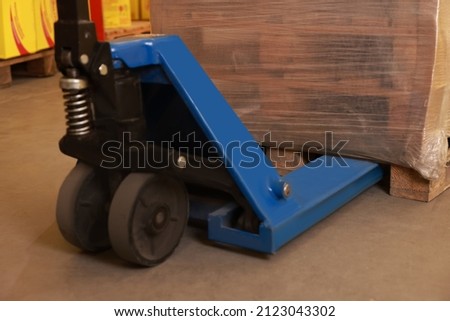 Wooden pallets wrapped in stretch on manual forklift indoors, closeup