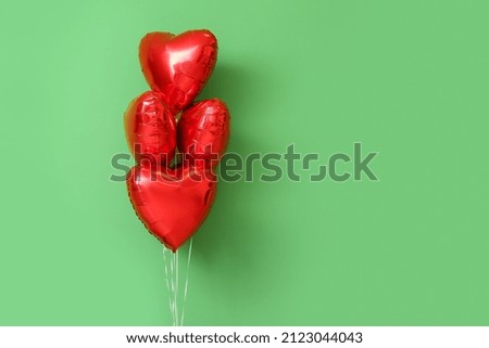 Beautiful heart-shaped balloons for Valentine's Day celebration on green background
