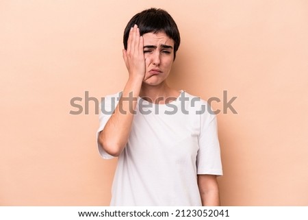 Young caucasian woman isolated on beige background tired and very sleepy keeping hand on head.